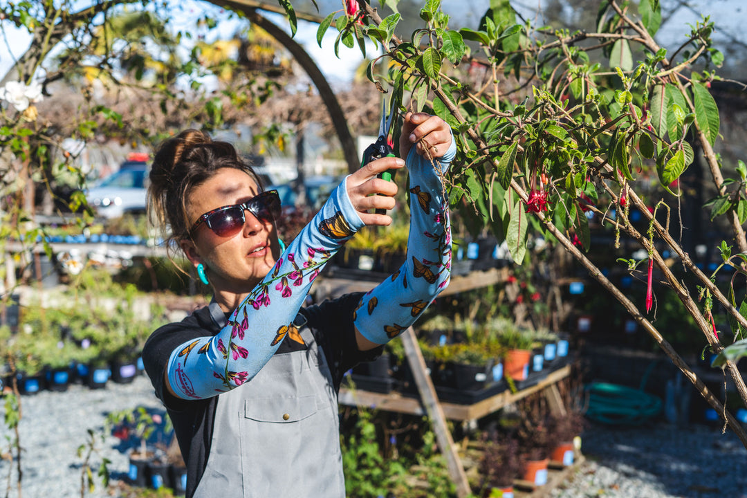 A woman trimming in her Farmers Defense UPF 50+ sleeves.