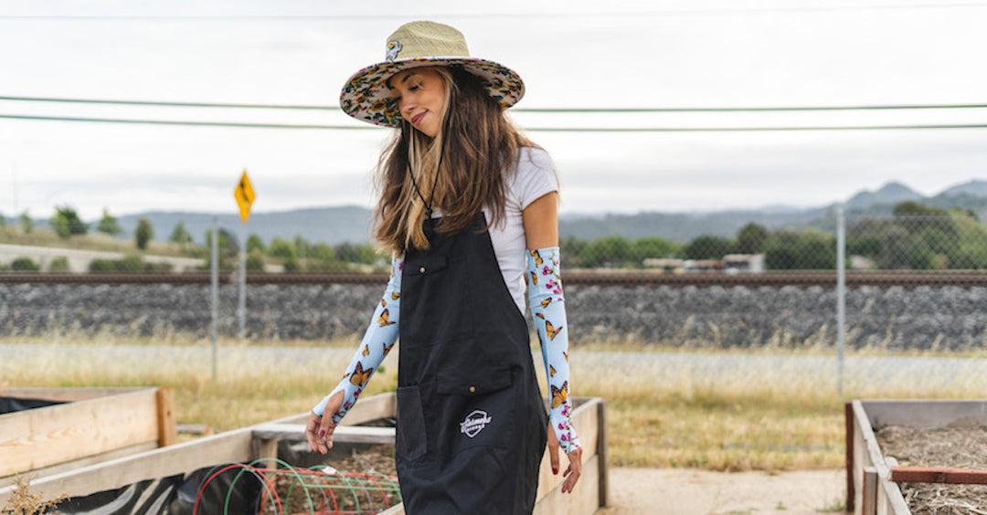A woman walking in between planters wearing protective gear. 